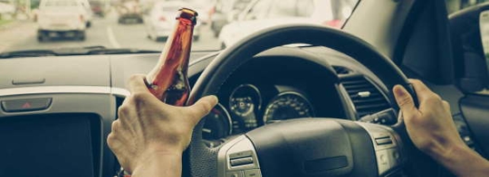 Driver holding a beer bottle at the wheel